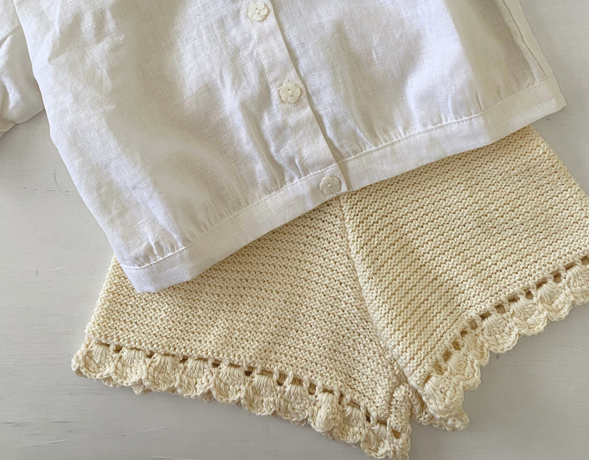 White shirt and beige knitted shorts with lace trim on a light wooden surface