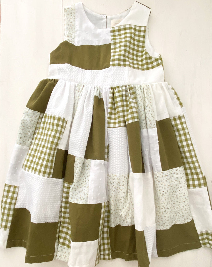 A flatlay image of the Mayday Patchwork dress, beautifully made using a combination of patterned and textured fabrics in green and white hues